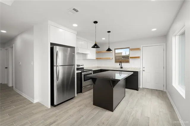 a kitchen with stainless steel appliances granite countertop a refrigerator a sink dishwasher a stove with wooden floors