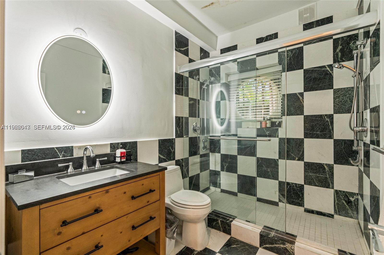 1951 Secoffee Street Miami, FL 33133 - Photo 20 of 24 a bathroom with a sink a toilet and a mirror