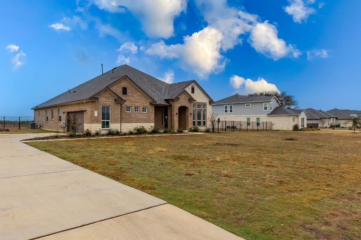French country style house featuring concrete driveway, brick siding, an attached garage, and a residential view