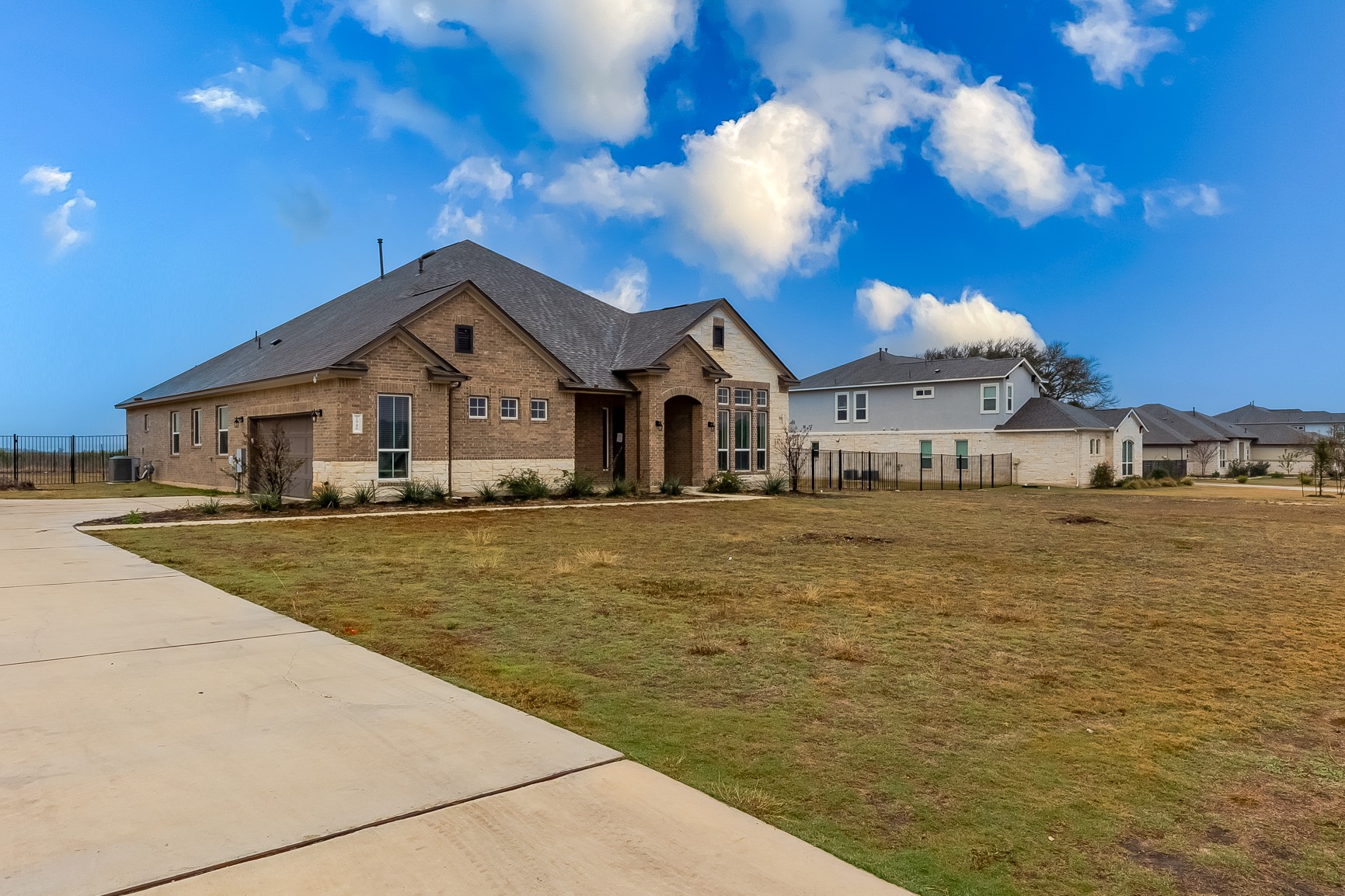 French country style house featuring concrete driveway, brick siding, an attached garage, and a residential view