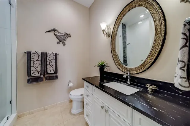 a bathroom with a granite countertop sink a toilet and a mirror