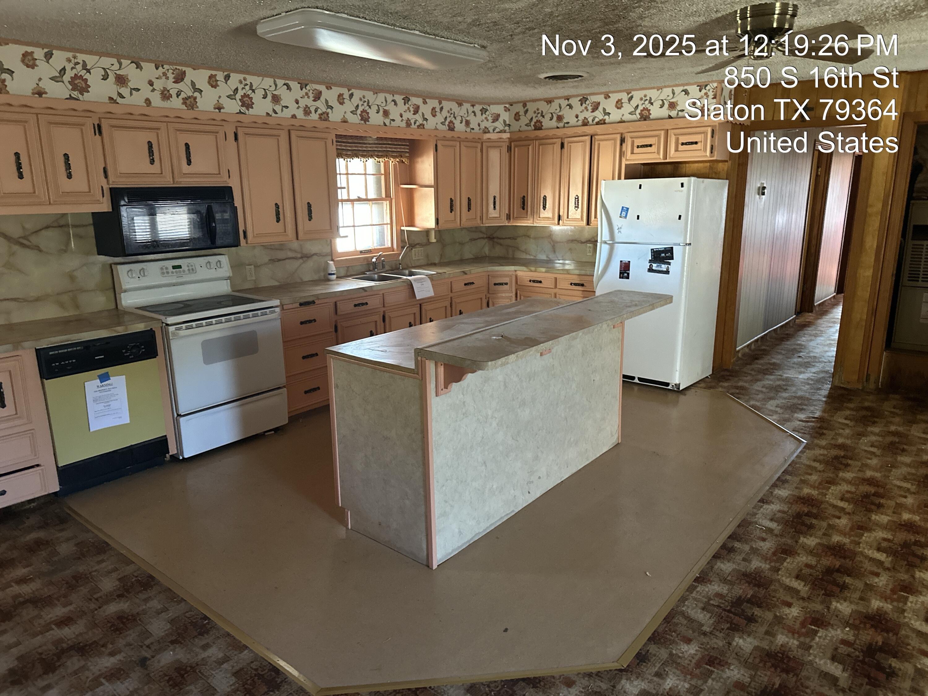 850 South 16th Street Slaton, TX 79364 - Photo 5 of 17 a kitchen with stainless steel appliances granite countertop a refrigerator a stove a sink and a microwave