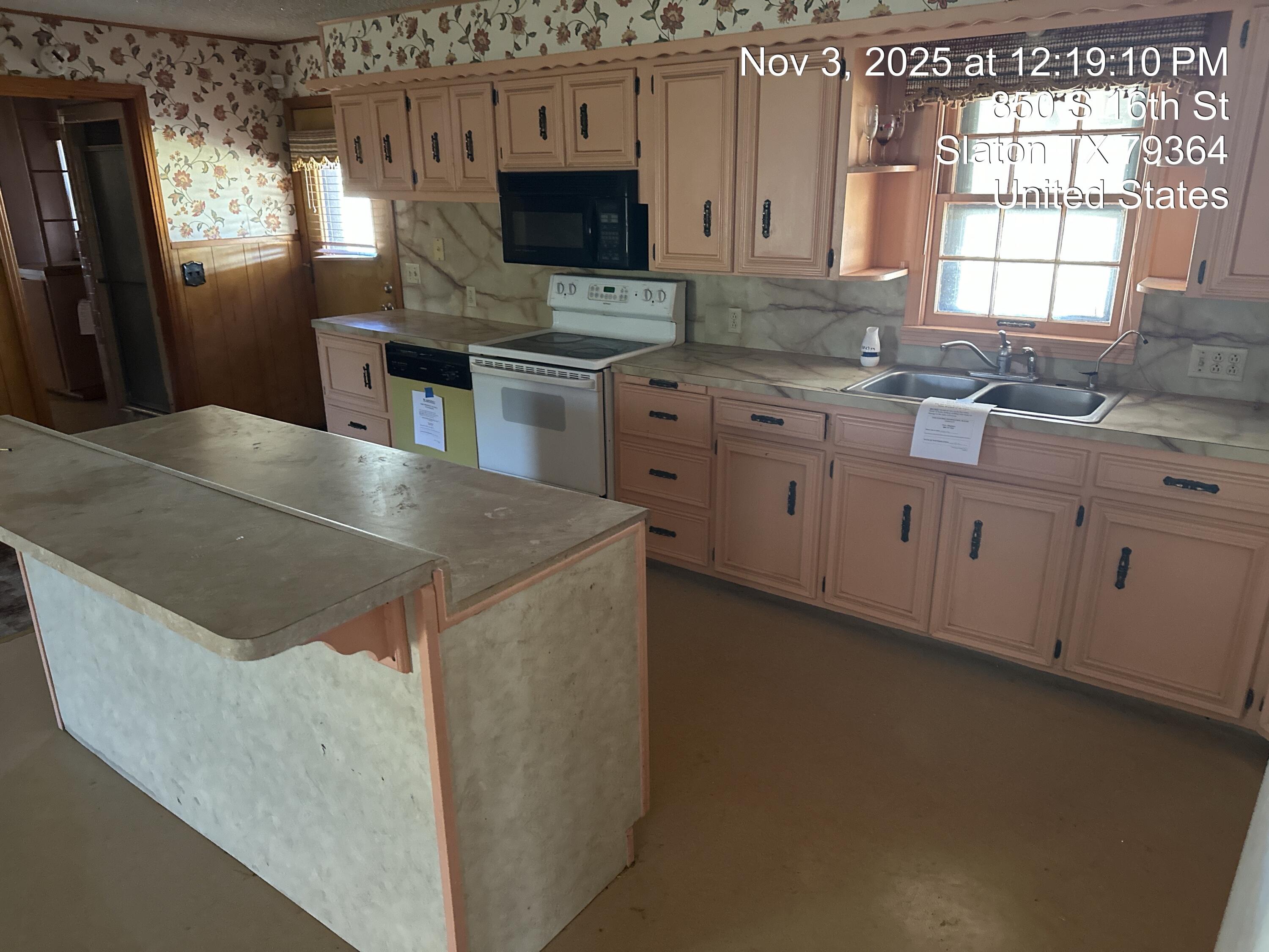 850 South 16th Street Slaton, TX 79364 - Photo 9 of 17 a kitchen with stainless steel appliances a stove a sink and a microwave