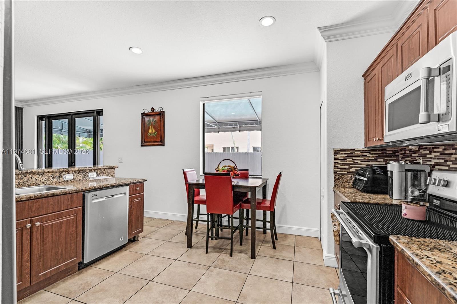 16610 Southwest 57th Lane Miami, FL 33193 - Photo 11 of 57 a kitchen with stainless steel appliances granite countertop a stove a sink a dining table and chairs