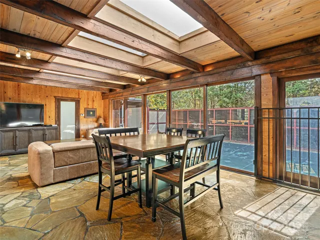 a living room with furniture a flat screen tv and floor to ceiling window