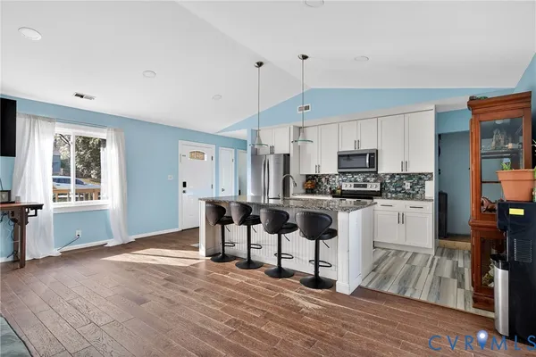 a kitchen with white cabinets and wooden floor
