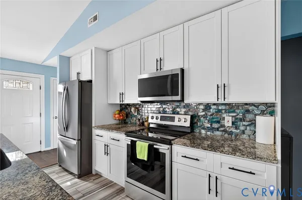 a kitchen with stainless steel appliances granite countertop a refrigerator and a stove top oven