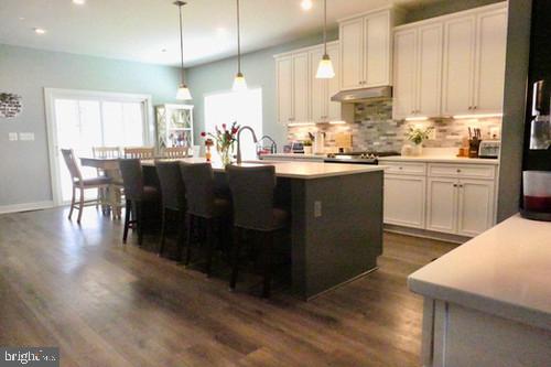 14905 Mapleridge Road Culpeper, VA 22701 - Photo 25 of 40 a kitchen with stainless steel appliances kitchen island granite countertop a refrigerator a stove a sink a dining table and chairs with wooden floor