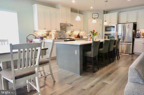 14905 Mapleridge Road Culpeper, VA 22701 - Photo 26 of 40 a kitchen with stainless steel appliances granite countertop a refrigerator a sink a stove and white cabinets with wooden floor