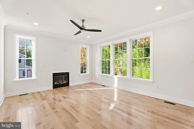 a view of an empty room with a window and wooden floor