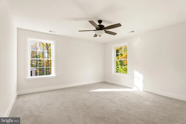 a view of empty room with window and ceiling fan