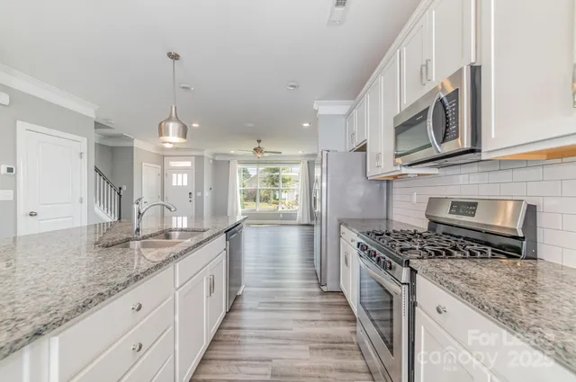 a kitchen with kitchen island granite countertop a sink refrigerator and microwave