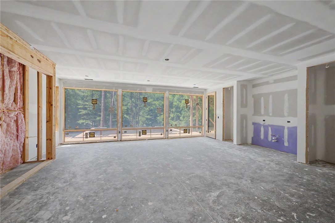 166 Ellenburg Creek Road Sunset, SC 29685 - Photo 14 of 20 A spacious room under construction reveals future possibilities, framed by tall windows overlooking lake, woods and outdoor pool area.