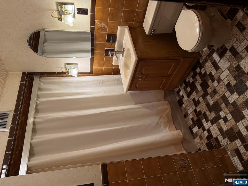 419 Elm Street, Unit 2 Kearny, NJ 07032 - Photo 8 of 8 a bathroom with a sink a toilet a mirror and shower curtain