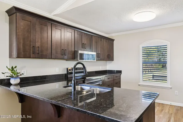 a kitchen with stainless steel appliances granite countertop a sink a microwave and wooden cabinets