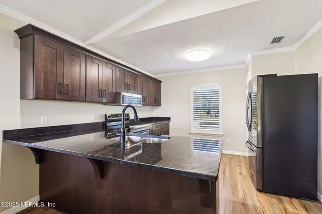 a kitchen with stainless steel appliances granite countertop a sink refrigerator and cabinets