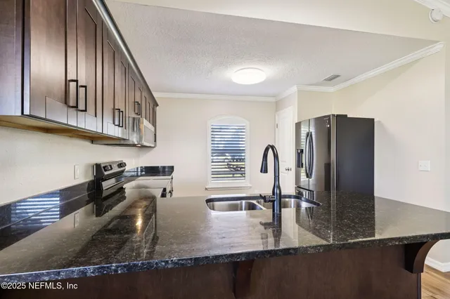 a kitchen with stainless steel appliances granite countertop a refrigerator a stove and a sink with wooden floor