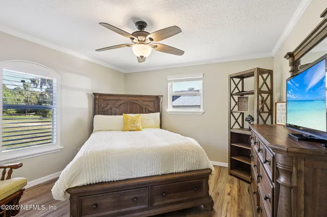 a bedroom with a bed and dresser with wooden floor