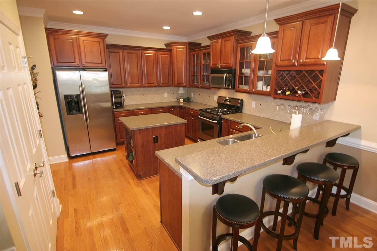 7334 Fontana Ridge Lane Raleigh, NC 27613 - Photo 10 of 24 a kitchen with stainless steel appliances a table chairs and a refrigerator