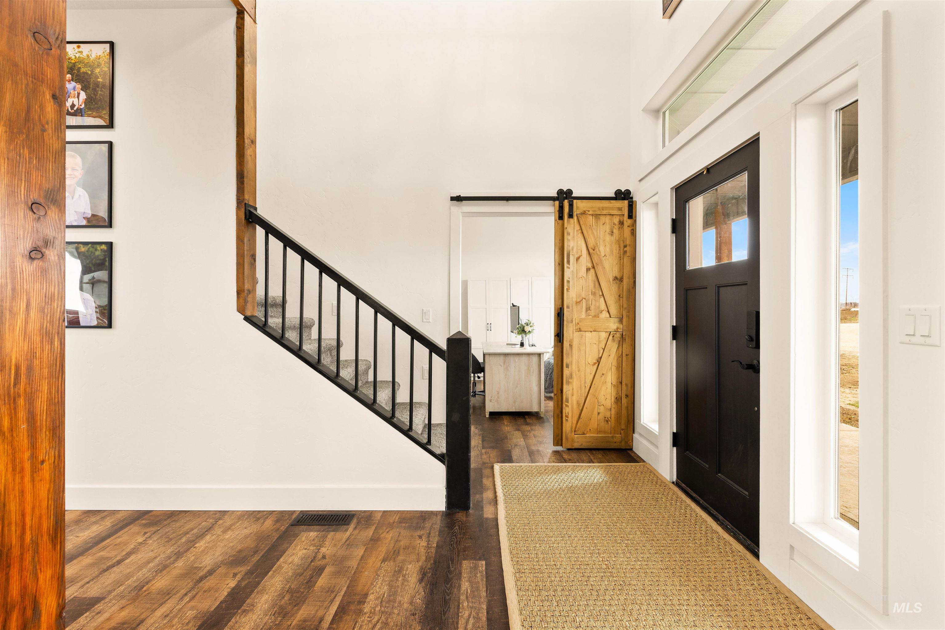 5220 West Central Road Emmett, ID 83617 - Photo 16 of 50 Entrance foyer featuring a barn door, dark wood-style flooring, and a high ceiling