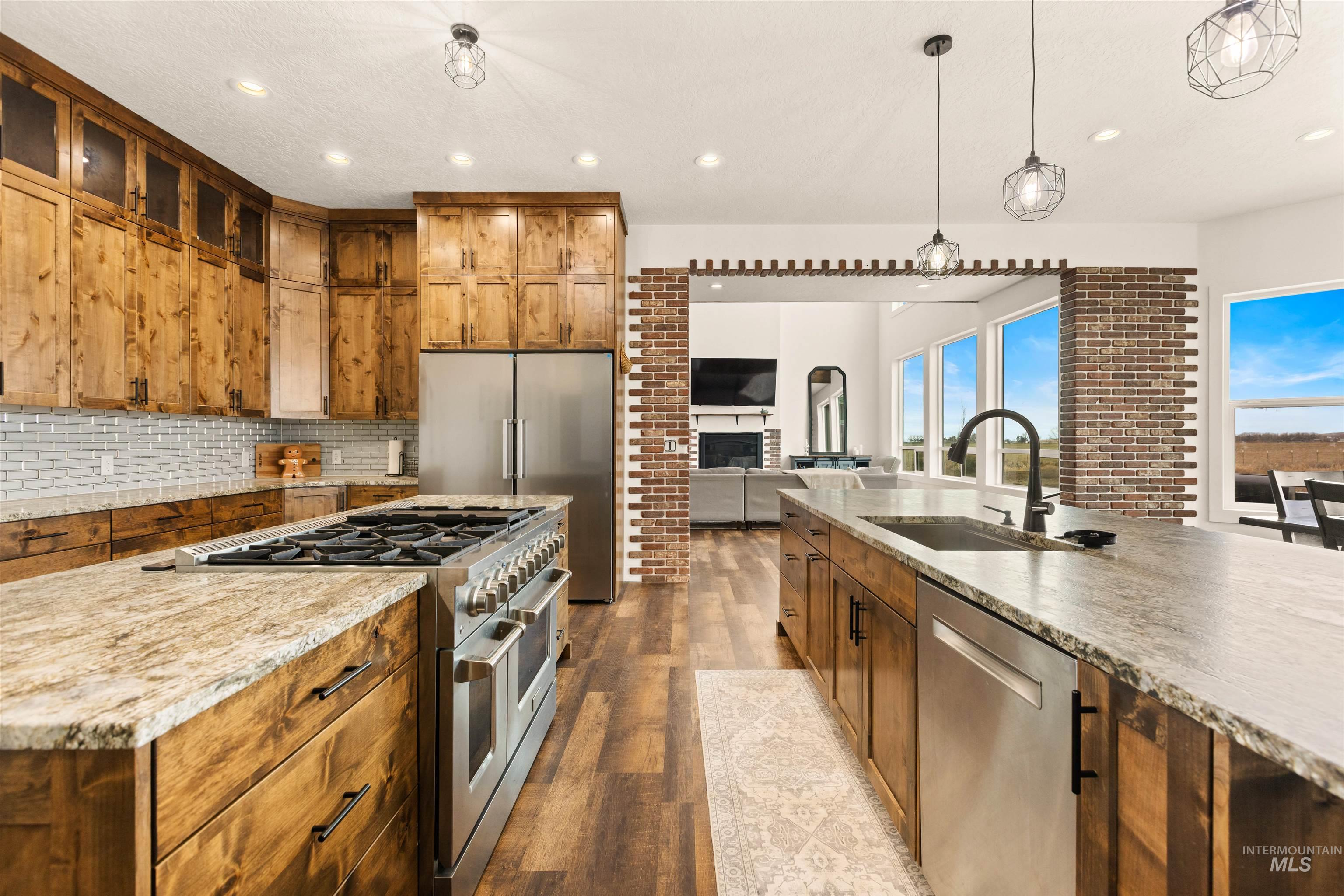5220 West Central Road Emmett, ID 83617 - Photo 17 of 50 Kitchen featuring stainless steel appliances, dark wood-type flooring, wood finish cabinetry, a fireplace, and light stone counters