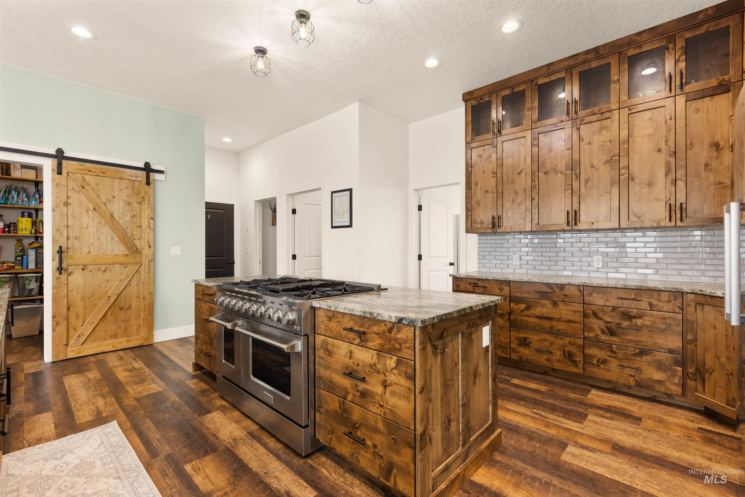 5220 West Central Road Emmett, ID 83617 - Photo 18 of 50 Kitchen with a barn door, double oven range, tasteful backsplash, glass insert cabinets, and wood finish cabinets