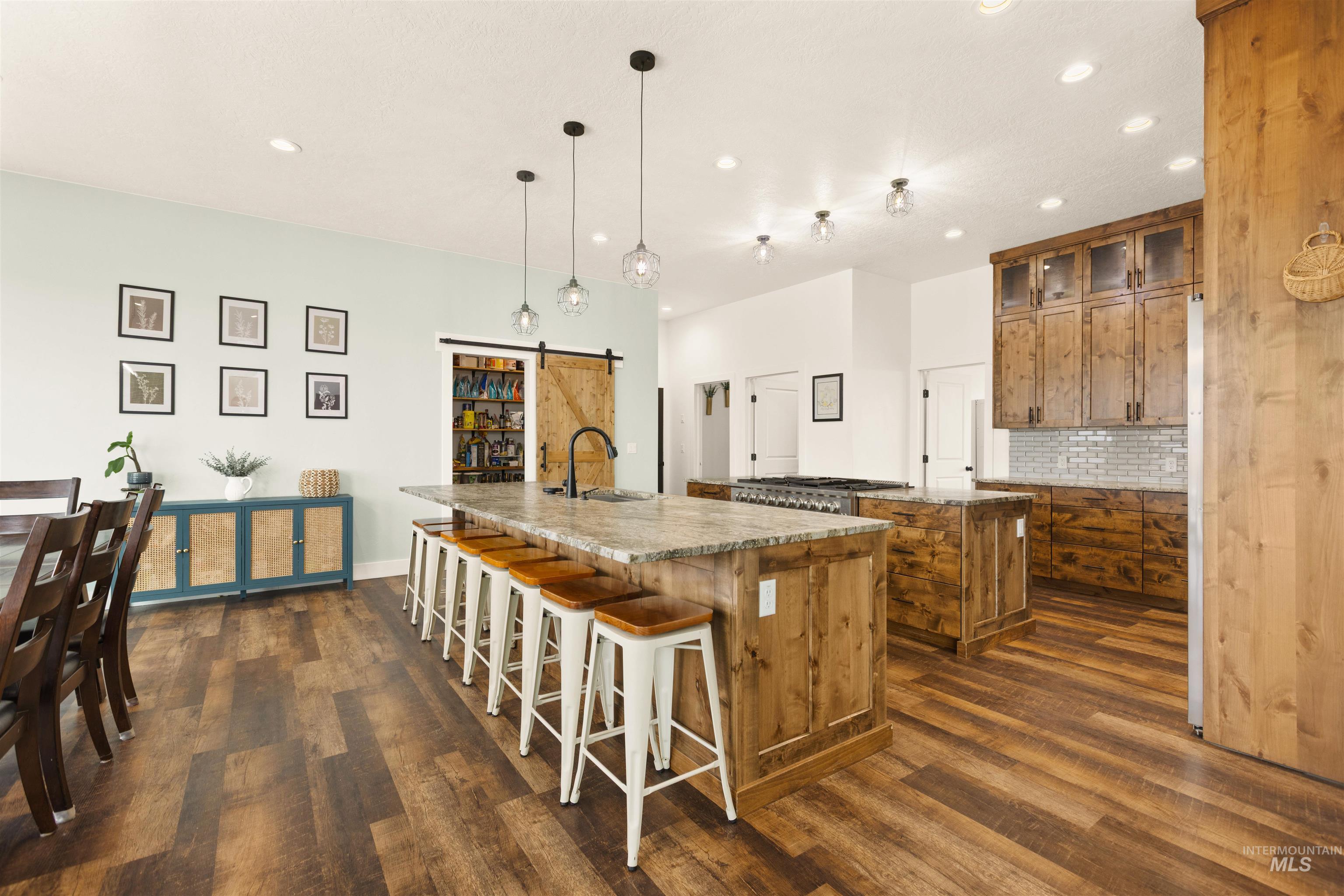 5220 West Central Road Emmett, ID 83617 - Photo 20 of 50 Kitchen with a barn door, wood finish cabinetry, decorative backsplash, glass insert cabinets, and a kitchen breakfast bar