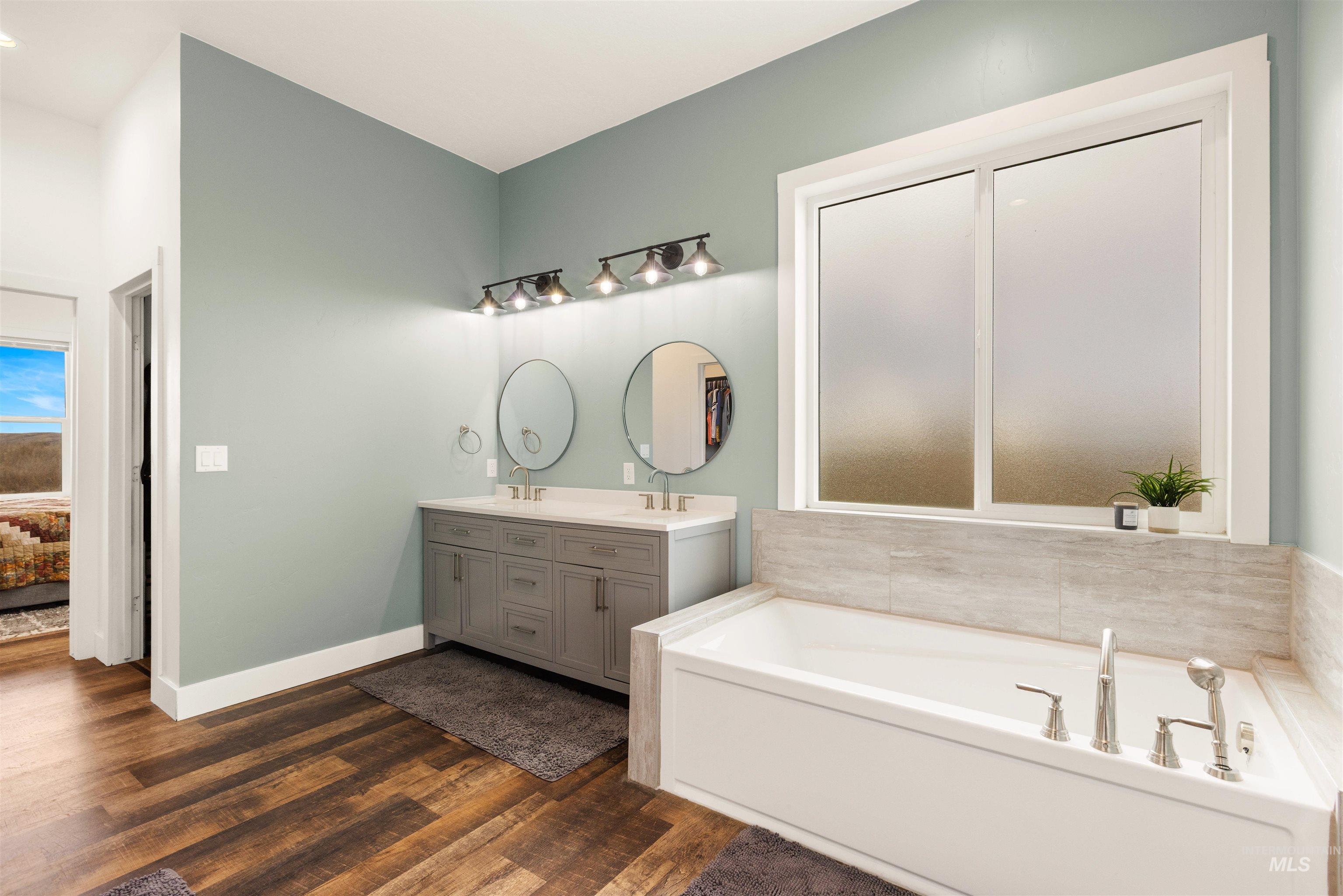5220 West Central Road Emmett, ID 83617 - Photo 27 of 50 Ensuite bathroom featuring double vanity, a bath, and dark wood-style flooring