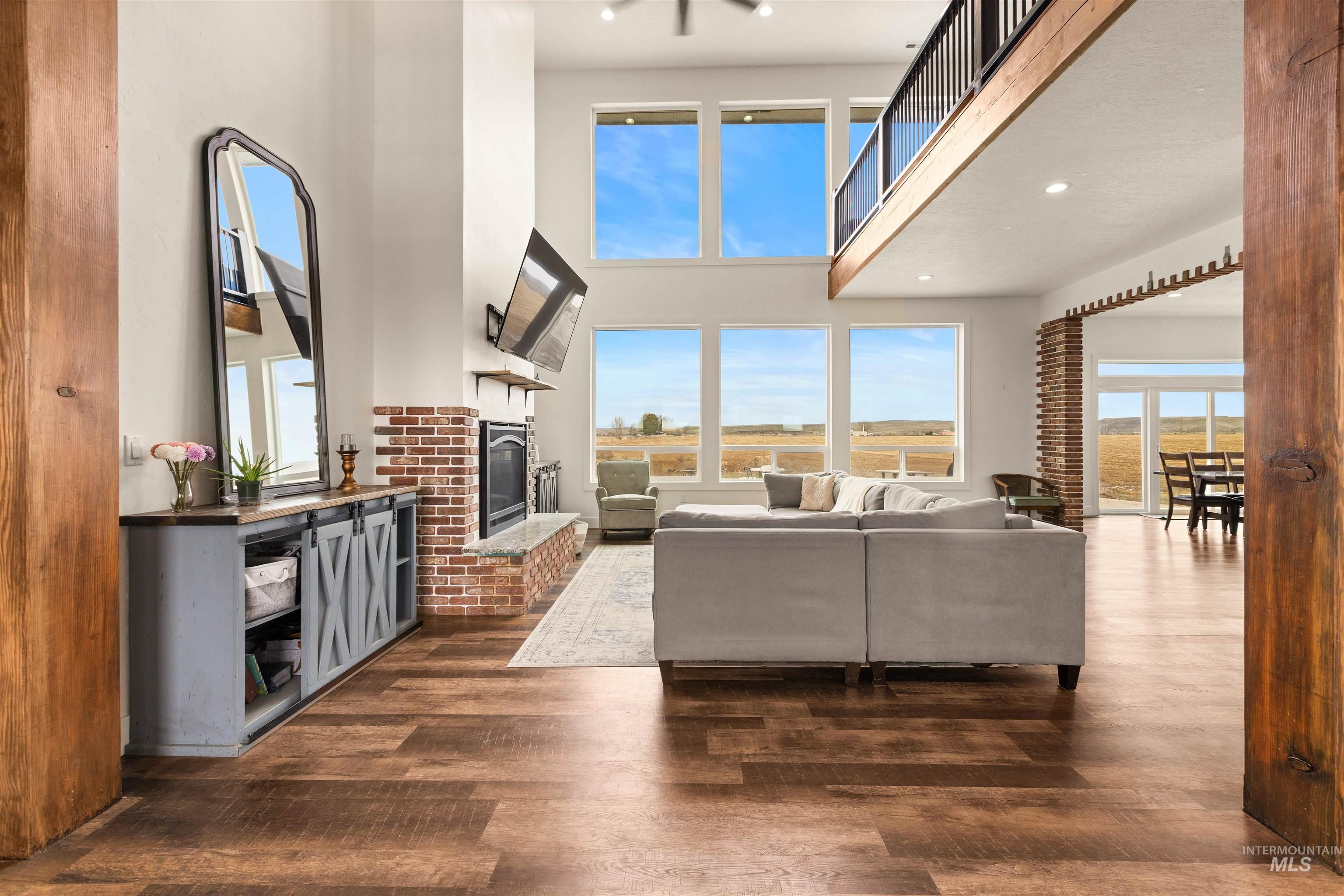 5220 West Central Road Emmett, ID 83617 - Photo 7 of 50 Living room with dark wood-style floors, a high ceiling, a brick fireplace, and recessed lighting