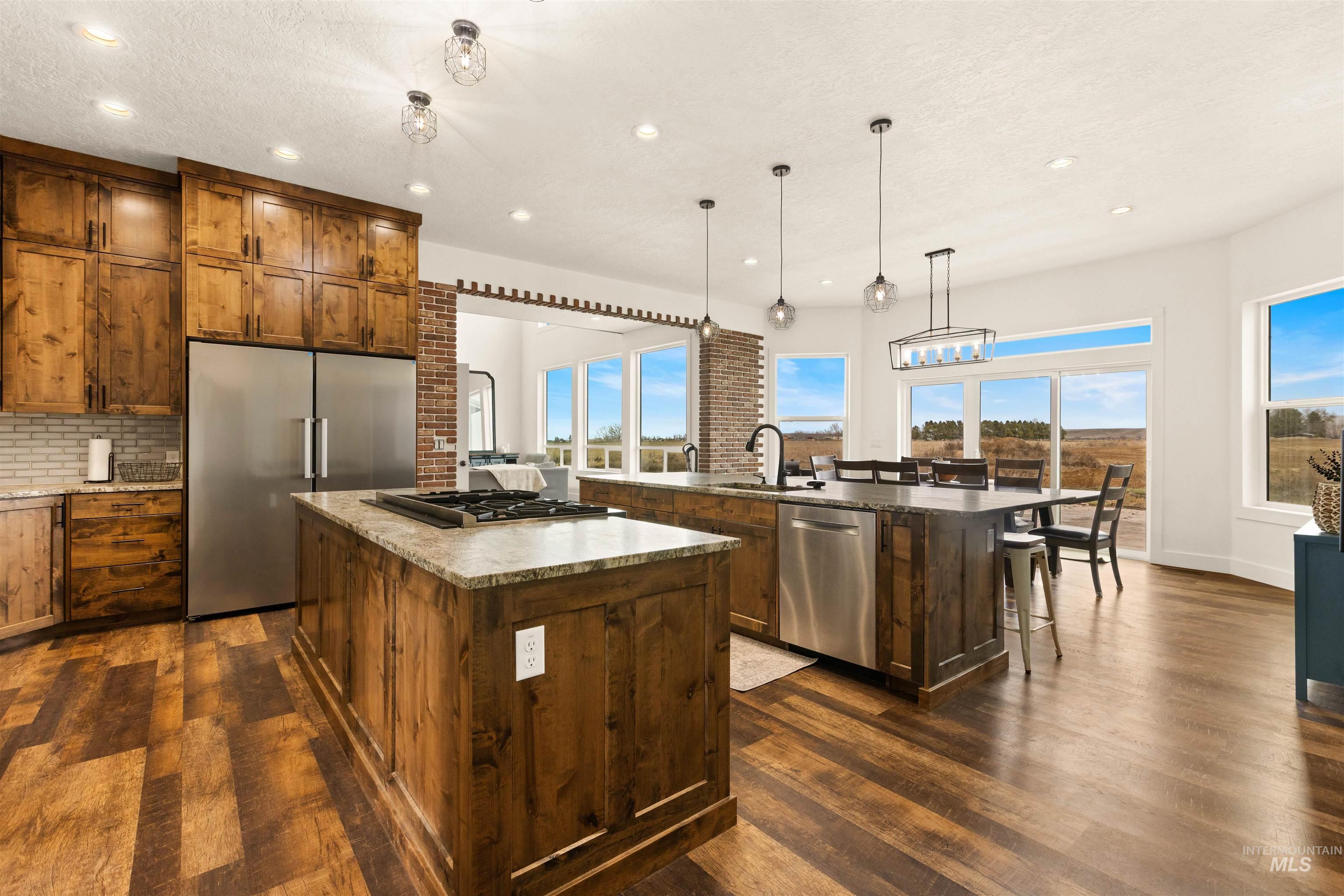 5220 West Central Road Emmett, ID 83617 - Photo 9 of 50 Kitchen with stainless steel appliances, dark wood finished floors, dark stone countertops, pendant lighting, and a breakfast bar