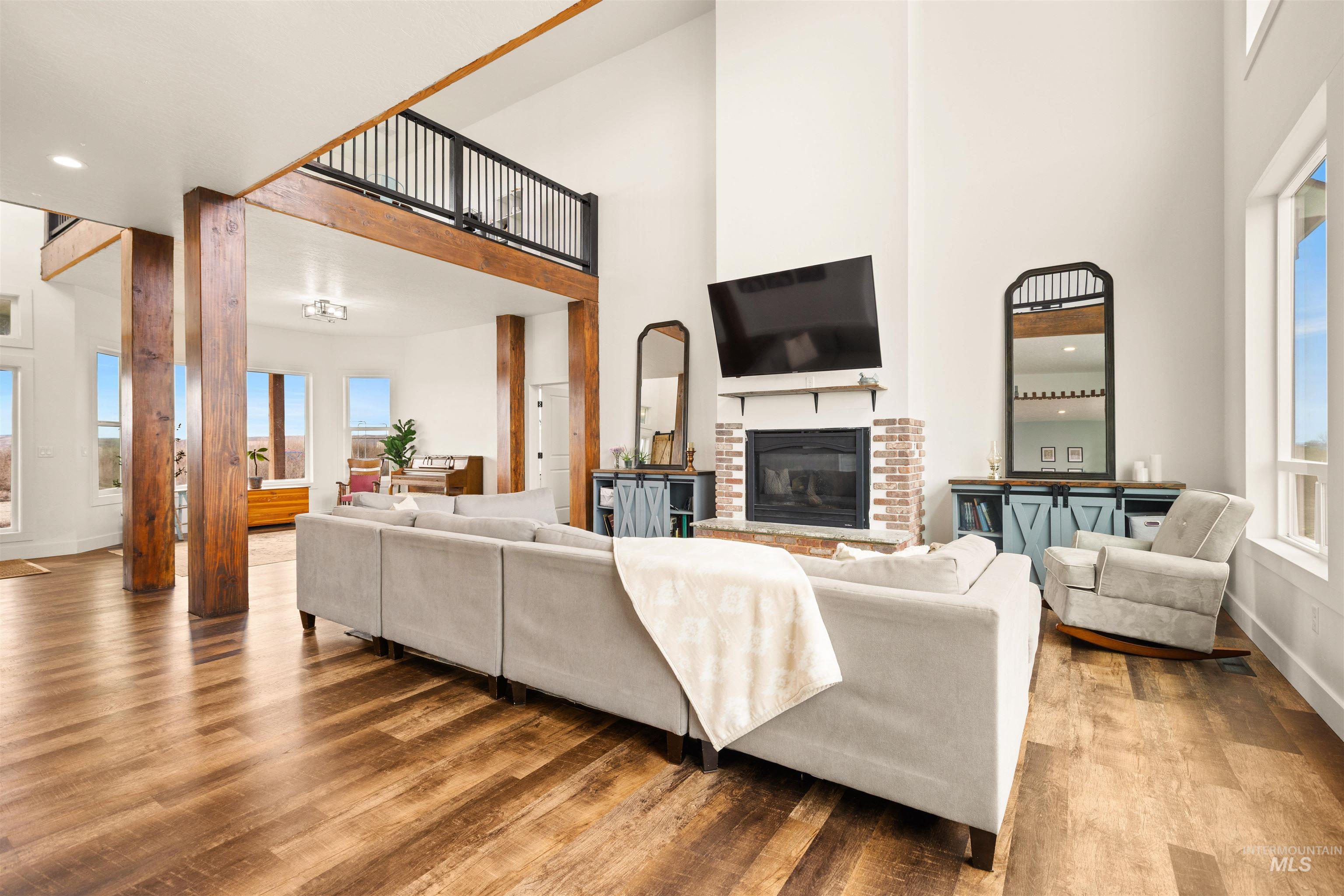 5220 West Central Road Emmett, ID 83617 - Photo 10 of 50 Living room featuring wood finished floors, a brick fireplace, a high ceiling, and recessed lighting