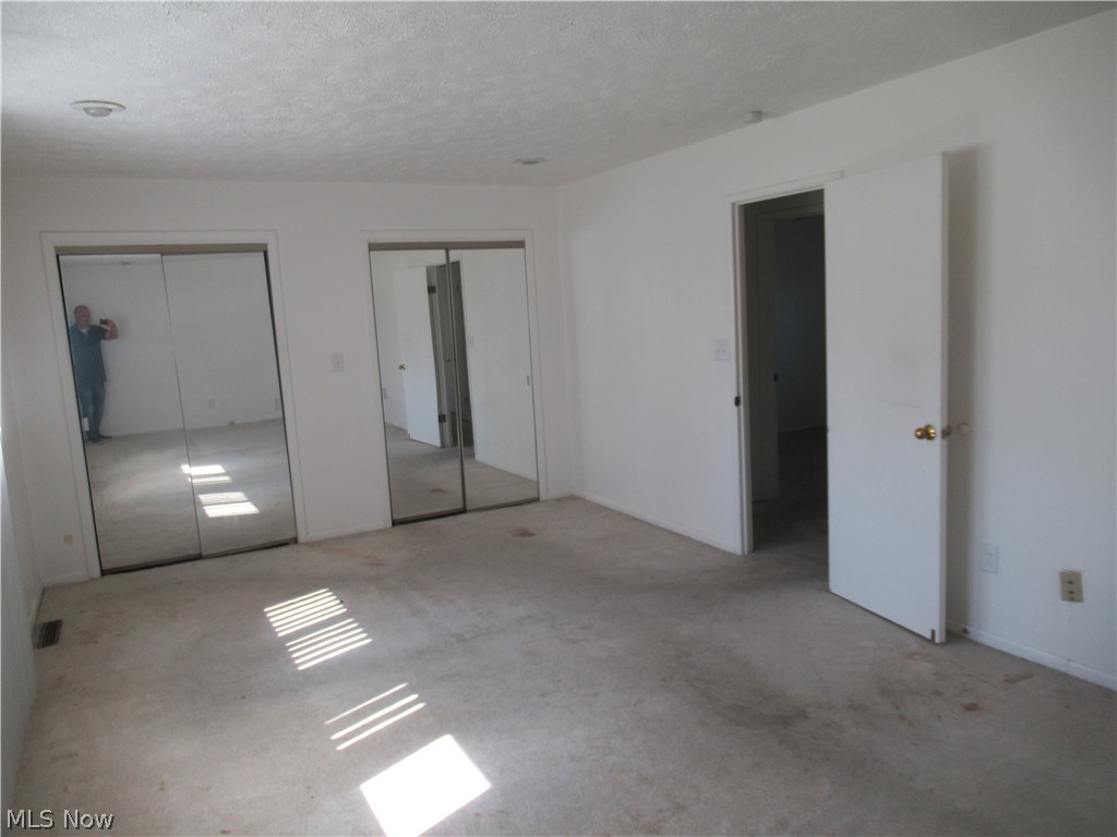 6033 Randy Road Bedford Heights, OH 44146 - Photo 13 of 19 Interior room featuring two mirrored sliding closet doors, white walls, and carpeted flooring
