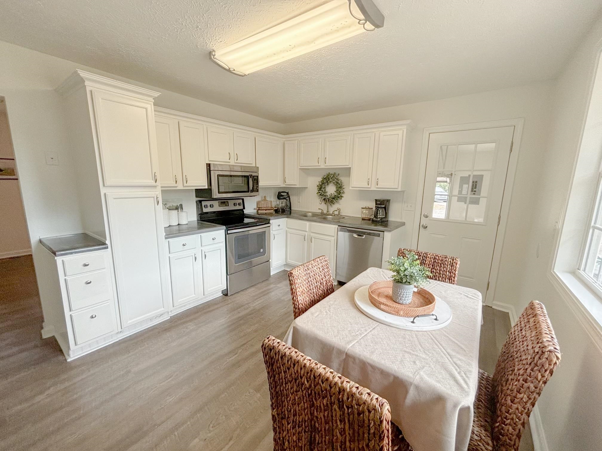 1695 Dawson Road Brighton, TN 38011 - Photo 6 of 13 Kitchen featuring light wood-type flooring, a textured ceiling, stainless steel appliances, sink, and white cabinets