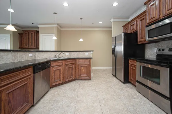 a kitchen with stainless steel appliances granite countertop a refrigerator a stove a sink and a microwave