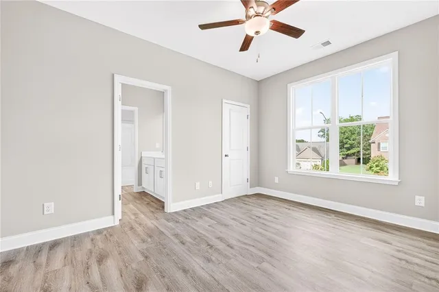 a view of an empty room with window and wooden floor