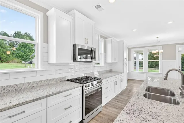 a kitchen with granite countertop a sink stainless steel appliances and cabinets