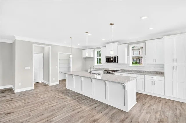 a large kitchen with cabinets wooden floor and stainless steel appliances