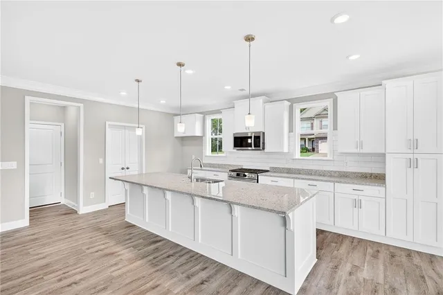 a large kitchen with stainless steel appliances granite countertop a stove a sink dishwasher and a wooden cabinets with wooden floor