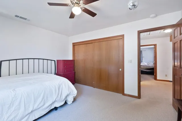 a bedroom with a large bed and a chandelier fan