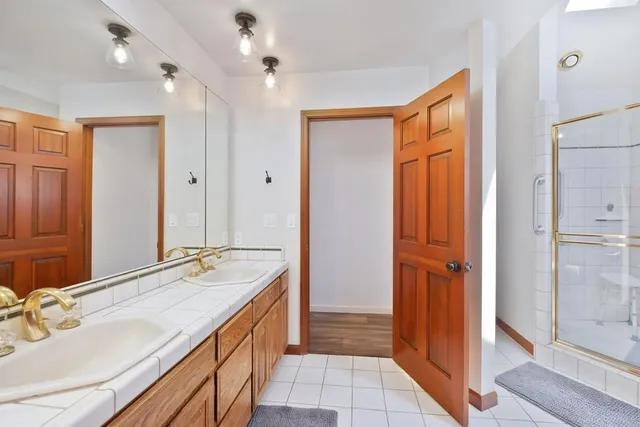 a bathroom with a double vanity sink a mirror and a shower