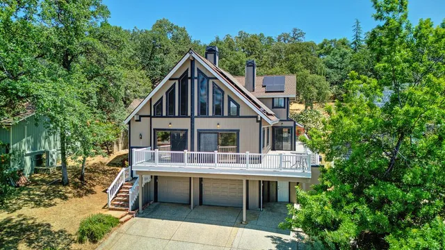 a view of house with a big yard plants and large trees