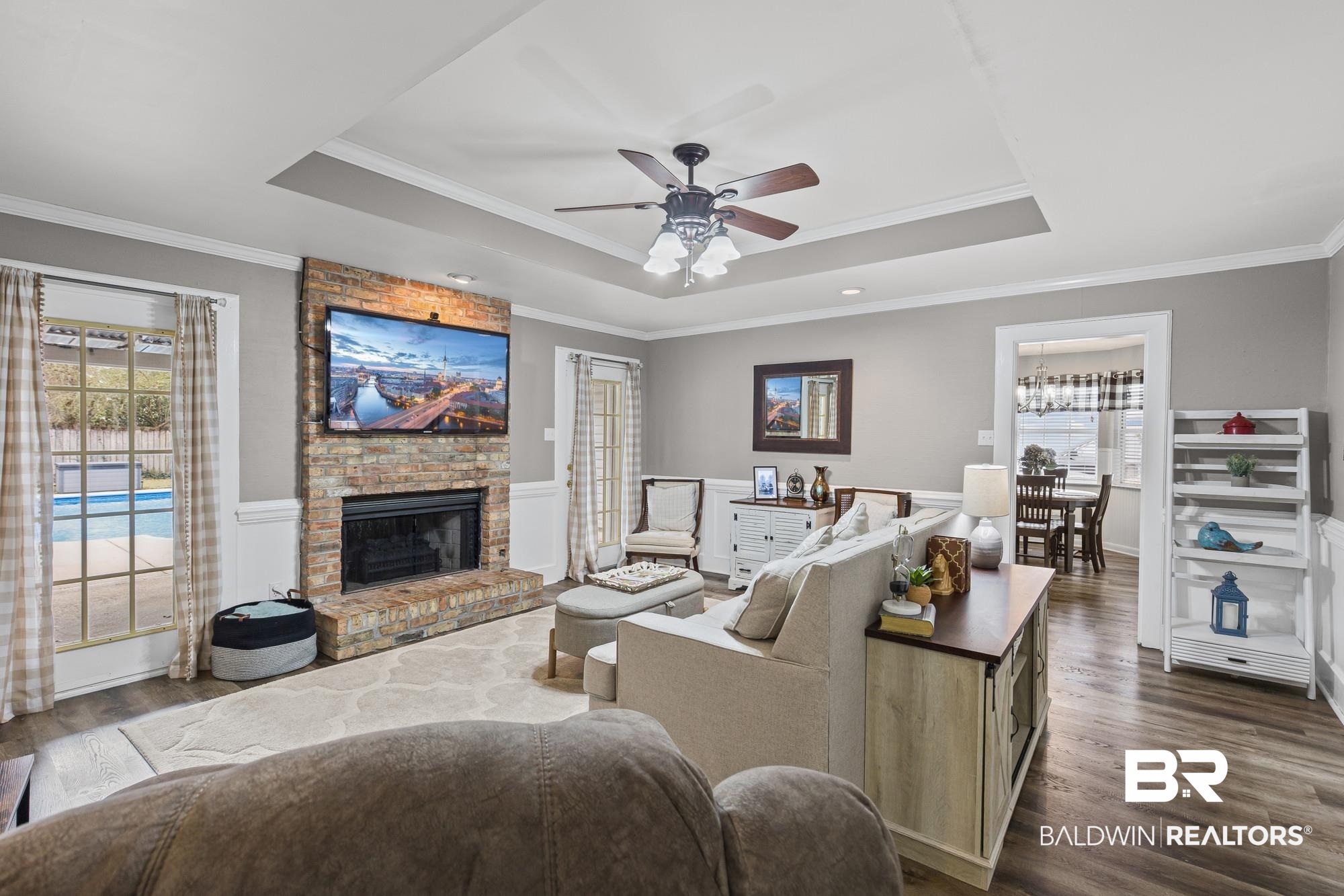 6609 Blakeley Court Mobile, AL 36695 - Photo 13 of 28 Living area featuring dark wood-type flooring, a fireplace, a ceiling fan, crown molding, and wainscoting