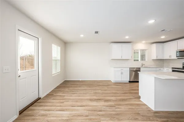 a open kitchen with white cabinets and wooden floor