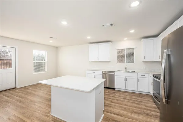 a kitchen with a sink a stove a refrigerator and white cabinets