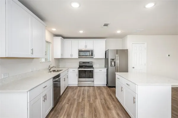 a kitchen with stainless steel appliances granite countertop a stove top oven a sink and a refrigerator