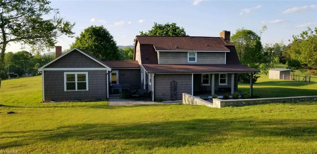 Front view surrounded by additional acreage.Mountain View can be enjoyed from back of the property.Larger dog and donkeys are in fenced area to the right.House's exterior is cedar and shakes with stone wall.