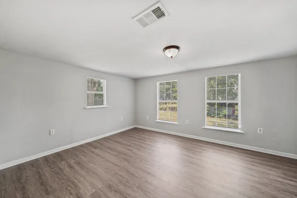 a view of an empty room with wooden floor and a window