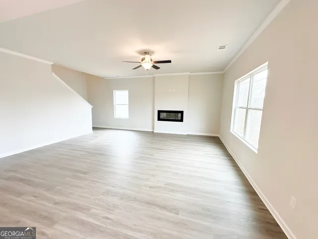 an empty room with wooden floor chandelier fan and windows