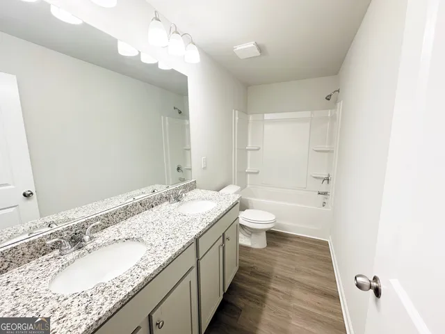a bathroom with a granite countertop double vanity sink a mirror and a bathtub
