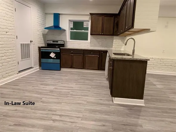a kitchen with stainless steel appliances granite countertop a sink wooden cabinets and a wooden floor